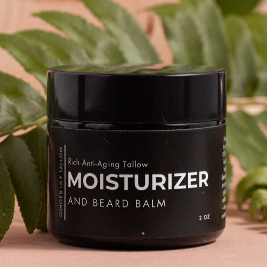 Black jar of moisturizer and beard balm with green leaves in the background