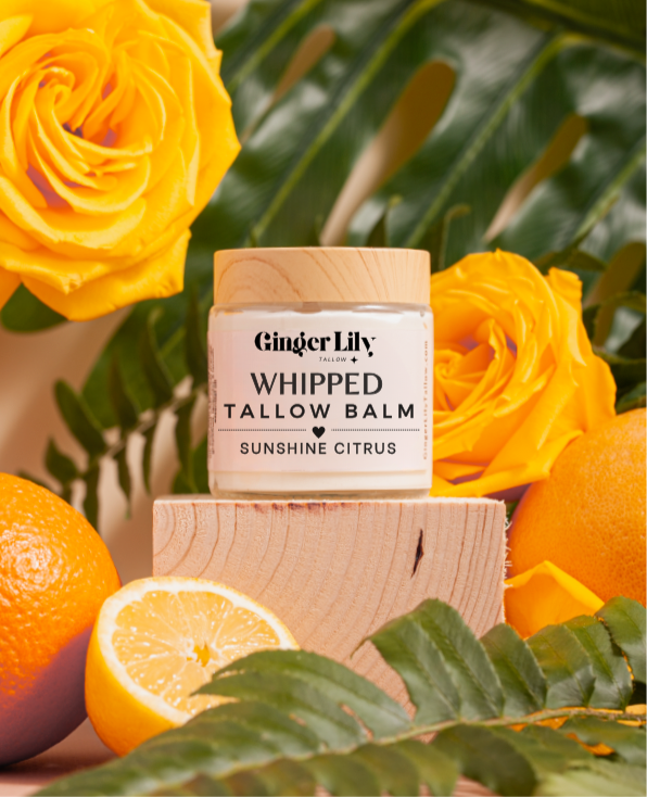 Organic beef tallow whipped tallow balm jar with yellow roses and oranges on a wooden block
