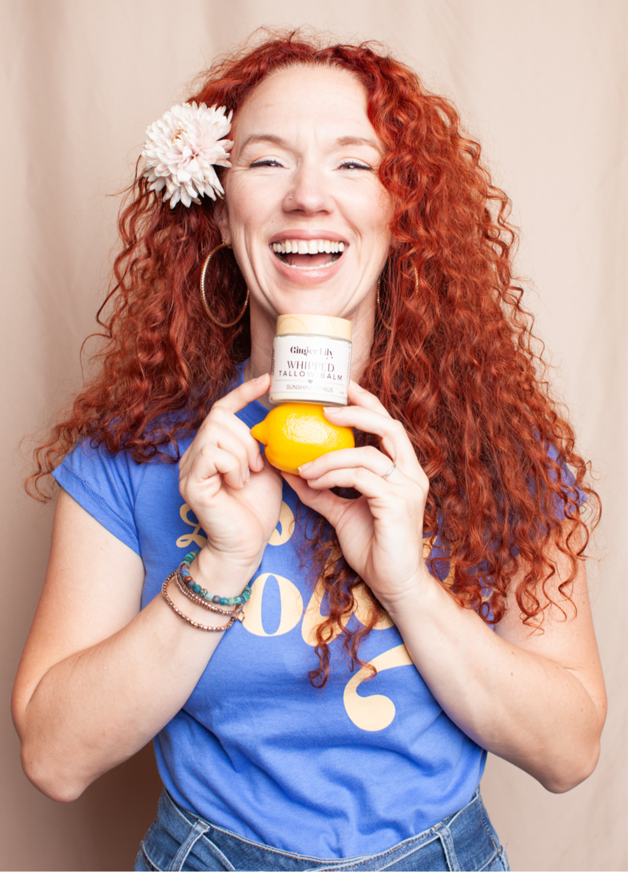 Owner of Ginger Lily Tallow holding a bottle of beef tallow against a beige background